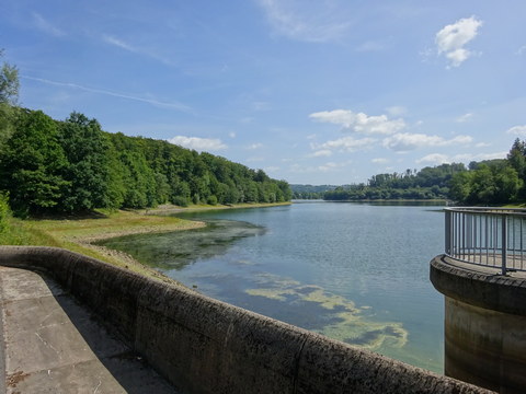 Eingebettet zwischen Wäldern und mit dem Überlauf im Vordergrund staut sich das Wasser der Lingesetalsperre