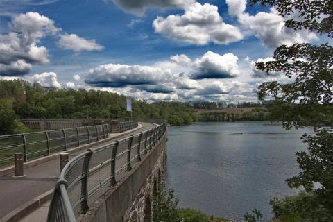 An einer bogenförmigen Bruchsteinmauer staut sich das Wasser der Ennepe