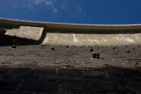Blick eine gewölbte Bruchsteinmauer hinauf zu einer darüberführenden Straße