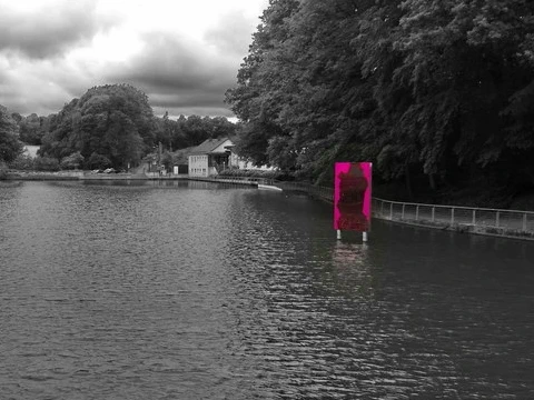 Eine bunte Metallplatte steht im Wasser eines Sees.