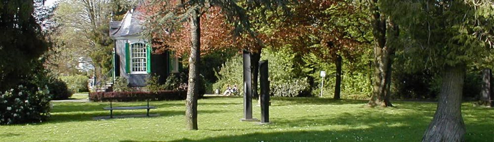 Parc de Chateaubriant. Auf einer Wiese zwischen Bäumen steht das Rokoko Gartenhäuschen