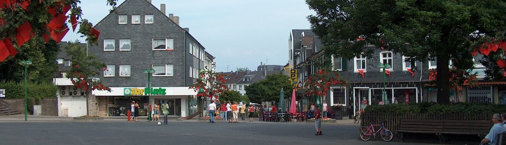 Blick über den Radevormwalder Marktplatz. An Häusern und Bäumen hängen kleine, rote Fähnchen