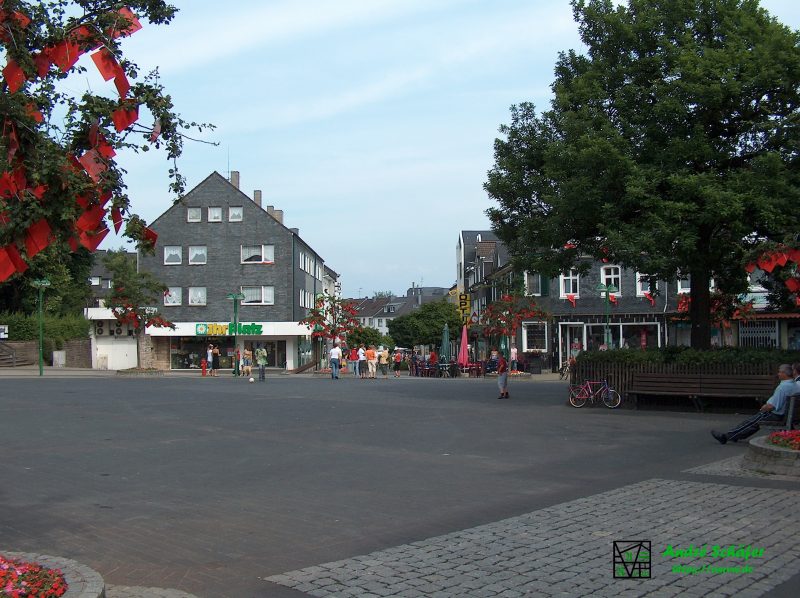 Blick über den Radevormwalder Marktplatz. An Häusern und Bäumen hängen kleine, rote Fähnchen