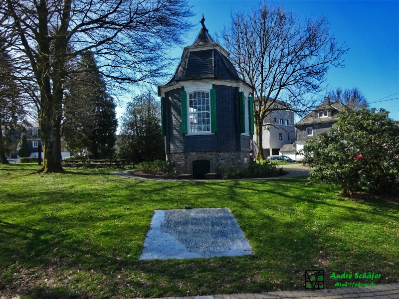 Parc de Chateaubriant mit Rokoko Gartenhäuschen. Im Vordergrund schützt eine große Glasplatte in der Wiese eine Kunstinstallation