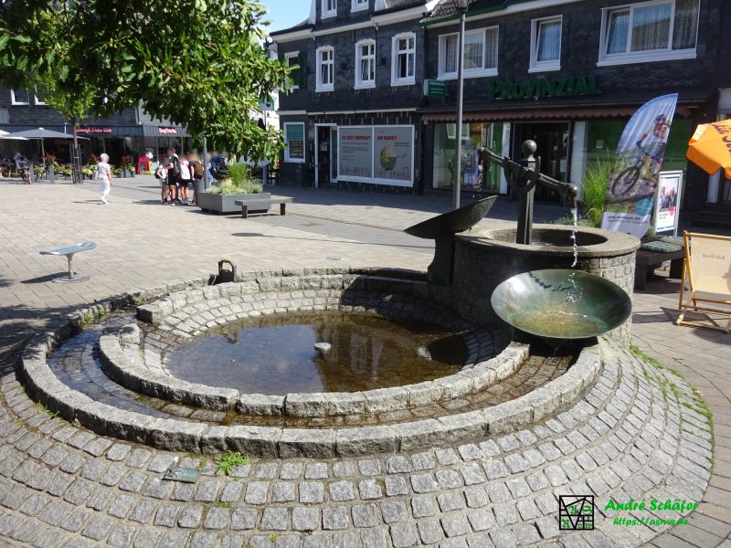 Der "Raybestos Brunnen" auf dem Radevormwalder Marktplatz. Aus dem Arm einer Waage plätschert Wasser in zwei große Bronzeschalen