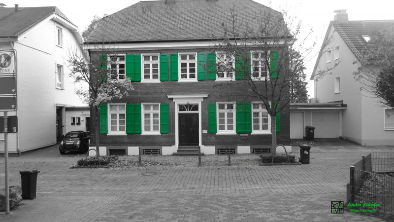 Ein typisch bergisches Haus an der Grabenstraße. Das ganze Bild ist schwarz-weiß, nur die grünen Schlagläden sind grün