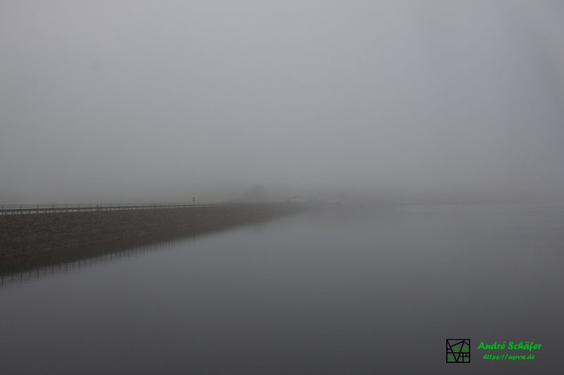 Links erkennt man den Beverdamm von der Wasserseite, der zur Bildmitte hin mehr und mehr im Nebel verschwimmt